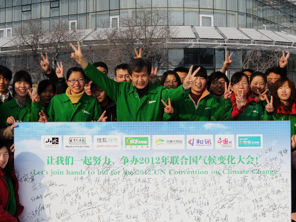 Huang Ming, NPC deputy, gestures March 1 before a sign board with his employees, urging China to host the 2010 UN climate change conference, in Dezhou of Shandong province. [CFP]