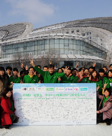 Huang Ming, NPC deputy, gestures before a sign board with his employees on March 1, urging China to host the 2010 UN climate change conference, in Dezhou of Shandong province. He owns a solar energy company in Shandong. [CFP]