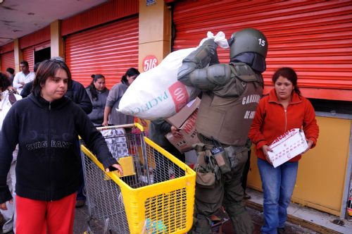 A policeman tries to keep order as people run away with looted merchandise in the quake-devastated Concepcion, Chile, March 1, 2010. Chilean security forces Monday arrested dozens of looters in Concepcion as hundreds of looters ransacked shops for food and other goods. The 8.8-magnitude quake occurring Saturday has killed over 700 people in Chile. [Martin Zabala/Xinhua] 