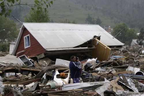 A woman holding a child stands among debris in earthquake-and-tsunami-devastated Dichato town, some 30 kilometers north of Concepcion, Chile, March 1, 2010. The death toll from the 8.8-magnitude earthquake that hit Chile early Saturday has reached 723, the Chilean government said on Monday. More than 500 people were injured and at least 19 people are still unaccounted for, the National Emergency Office (Onemi) said. [Victor Rojas/Xinhua] 