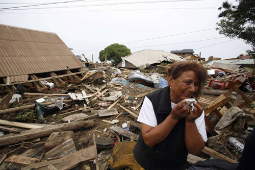 A woman cries while inspecting her home destroyed by a major earthquake in Iloca, March 1, 2010. [Xinhua] 