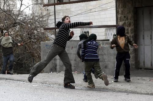 Palestinian protesters throw stones towards Israeli soldiers during clashes in the West Bank city of Hebron, Feb. 24, 2010. Palestinians in Hebron continued to protest Wednesday against Israel's decision to recognize a disputable West Bank shrine as one of its national heritage sites. Palestinian President Mahmoud Abbas warned Tuesday that the region could plunge into a 'religious war' over the decision. [Xinhua photo]  