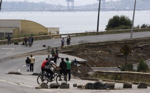 People walk on a destroyed road after tsunami and the 8.8-magnitude earthquake in Lota Port, 60km south Concepcion, Chile, March 2, 2010. Chilean President Michelle Bachelet said Tuesday that the death toll from Saturday's devastating earthquake had reached 795. [Victor Rojas/Xinhua]