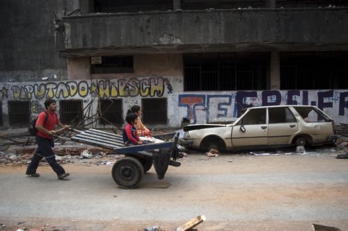 People pass by damaged houses after tsunami and the 8.8-magnitude earthquake in Lota Port, 60km south Concepcion, Chile, March 2, 2010. Chilean President Michelle Bachelet said Tuesday that the death toll from Saturday's devastating earthquake had reached 795. [Victor Rojas/Xinhua]