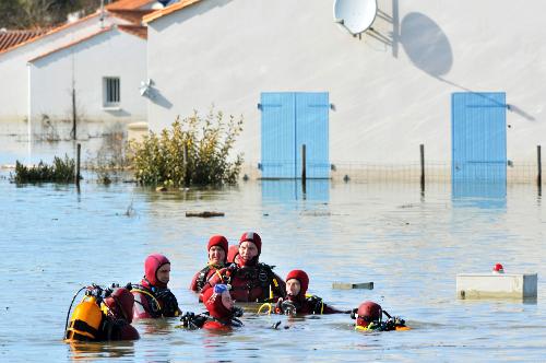 Rescue workers search for the missing in a flooded residential neighborhood in La-Faute-sur-Mer, western France, March 2, 2010 after a major storm named Xynthia hit western Europe. [Xinhua] 