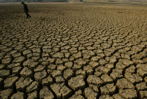 A man walks on a dried-up reservoir in Caoba Town of Mengzi County, southwest China&apos;s Yunnan province, March 1, 2010. Continual drought has hit the county of Honghe Hani and Yi Autonomous Prefecture, since September 2009, resulting in serious water shortage. [Xinhua]