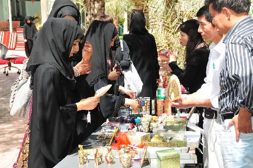 Students appreciate Chinese traditional craftwork during the Chinese Cultural Week at the Zayed University in Abu Dhabi, capital of the United Arab Emirates (UAE), March 3, 2010. The five-day-long Chinese Cultural Week will promote Chinese culture with the presentation of the traditional art, music, calligraphy, painting, food, language education and martial art.