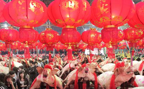 Visitors enjoy their time when walking between lanes of pigs on display during a local traditional folk fair named &apos;Pig Contest&apos; at Guanshan Village in Shantou City, south China&apos;s Guangdong province, March 2, 2010. [Xinhua]