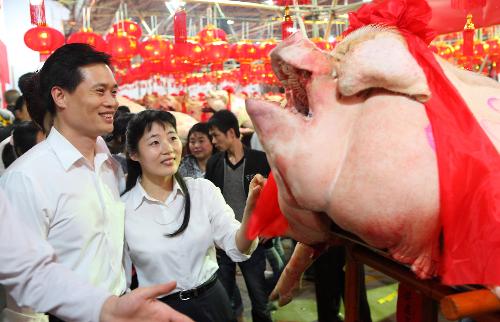 A young couple admire a big fat pig during a local traditional folk fair named &apos;Pig Contest&apos; at Guanshan Village in Shantou City, south China&apos;s Guangdong province, March 2, 2010. [Xinhua]