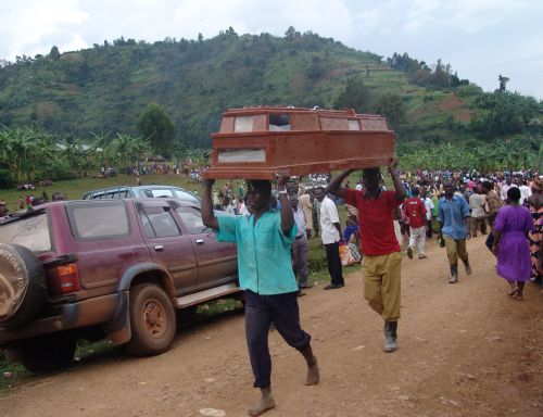 Two men carry a coffin of a victim of the landslide at Nametsi village in Bududa District, about 370 kilometers east of the Ugandan capital Kampala, on March 3, 2010. Soldiers and villagers in eastern Uganda hacked at mounds of thick mud with picks and hoes on Wednesday in a desperate bid to find more survivors from the landslide that killed at least 77 people and left over 250 missing. [Julius Odeke/Xinhua]