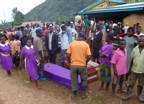 School girls pass by coffins of victims of the landslide at Nametsi village in Bududa District, about 370 kilometers east of the Ugandan capital Kampala, on March 3, 2010. Soldiers and villagers in eastern Uganda hacked at mounds of thick mud with picks and hoes on Wednesday in a desperate bid to find more survivors from the landslide that killed at least 77 people and left over 250 missing. [Julius Odeke/Xinhua]