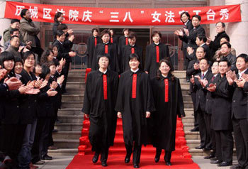 Women judges show their robes on the red carpet to mark the International Women's Day, which falls on March 8, in Jinan, capital city of east China's Shandong Province, March 4, 2010. [Xinhua] 