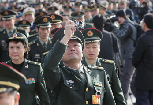 A deputy (front) to the Third Session of the 11th National People's Congress (NPC) takes pictures while walking to the Great Hall of the People in Beijing, capital of China, March 5, 2010. The Third Session of the 11th NPC opened on Friday. [Xing Guangli/Xinhua]