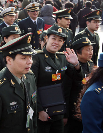 A female deputy (C) to the Third Session of the 11th National People's Congress (NPC) gestures to camera while walking to the Great Hall of the People in Beijing, capital of China, March 5, 2010. The Third Session of the 11th NPC opened on Friday. [Wang Jianmin/Xinhua]