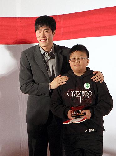 China&apos;s 110m hurdle athlete Liu Xiang (L) poses for a photo with a boy during an event to promote environmental protection for the 2010 Shanghai World Expo in Shanghai, February 10, 2010. [Xinhua]