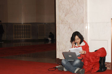 A reporter is busy with her work during the opening meeting of the Third Session of the 11th National People's Congress, March 5th. [Fan Wenjun / womenofchina.cn]