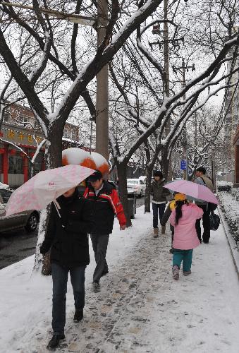 Local residents walk on the snow-covered Tonglin'ge Road in Beijing, March 8, 2010. Snowfall began hitting the Chinese capital Sunday night and is continuing to fall Monday morning. [Xinhua] 