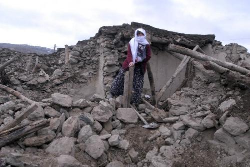 A woman stands in front of her destroyed house in Karakocan, in the southeastern Elazig province.[Xinhua]