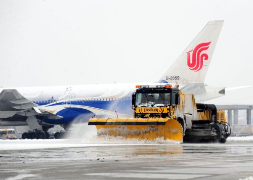 A bulldozer shovels the snow away from the apron at the Beijing Capital International Airport in Beijing, capital of China, March 8, 2010. The urban area of Beijing had received 4.2 millimeters of snow Monday. By Monday morning, 49 flights had been canceled and 28 others delayed because of the snow. [Xinhua]