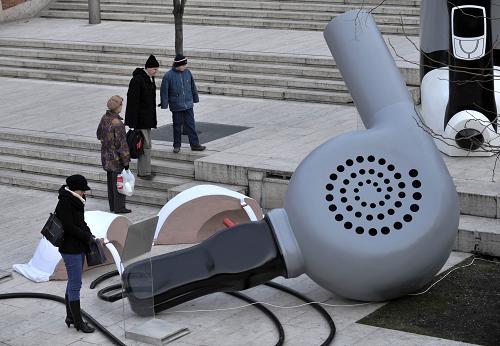 Spectators walk by a giant sculpture of a hair drier at an open air exhibition entitled &apos;&apos;The Magnificent Innovations for Women&apos;&apos; in Budapest. [Xinhua/AFP]