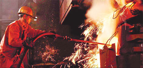 An employee working at a steel furnace in Dalian. China's iron ore production stood at 200 million tons in 2009 and is likely to rise by 20 percent this year. [China Daily]