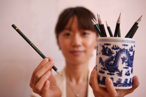A journalist displays recycled-paper-made pens, which are served at the Great Hall of the People, venue of the annual sessions of the 11th National People's Congress and the 11th National Committee of the Chinese People's Political Consultative Conference (CPPCC) in Beijing, China, March 10, 2010.
