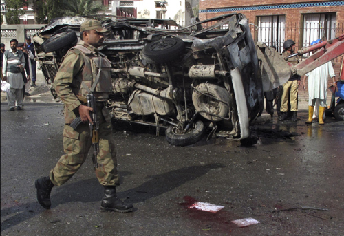A soldier walk past a damaged vehicle at the site of a suicide bomb attack in Mingora, located in Pakistan's restive North West Frontier Province on March 13, 2010. A suicide bomber targeting security forces in Pakistan's Swat Valley on Saturday killed at least 14 people, police said, part of a renewed Taliban push against the government after a major crackdown against the group. [Xinhua]