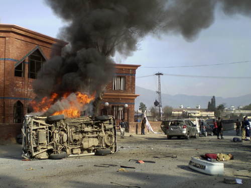 A vehicle burns as bodies of victims lie near the site of a suicide bomb attack in front of the Circuit House in Mingora, located in Pakistan&apos;s restive North West Frontier Province March 13, 2010. The suicide bombing attack on security forces in Pakistan&apos;s Swat Valley on Saturday killed at least 14 people and wounded 13, police said. [Xinhua] 