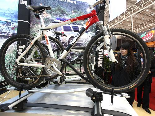 A visitor looks at bicycles carried on the top of vehicles at the automotive aftermarket fair in Beijing, China, March 12, 2010. [Luo Wei/Xinhua]