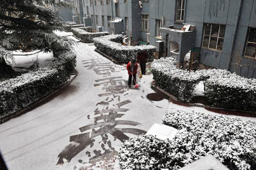 Two women clean up snow in the Lugu residential area in Beijing, capital of China, March 14, 2010. A sleet hit Beijing Sunday morning. [Photo: Xinhua]