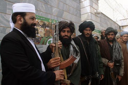 An Afghan official (1st L) receives weapons handed by Taliban fighters when they defect to the government in Shindand district of Herat province, Afghanistan, on March 14, 2010. Thirty Taliban fighters defected to the government here on Sunday. [Melad/Xinhua] 