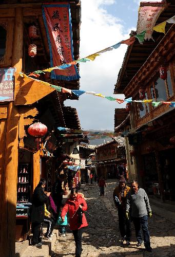 People roam on a street in Dukezong ancient city of Shangri-la County, southwest China's Yunnan Province, on March 12, 2010. Dukezong, which has a history of 1,300 years, means 'Moonlight City' in the Tibetan language. [Xinhua/Lin Yiguang]