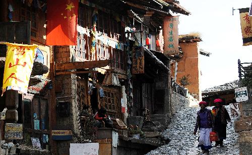 Two women of China's Tibetan ethnic group walk on a street in Dukezong ancient city of Shangri-la County, southwest China's Yunnan Province, on March 12, 2010. Dukezong, which has a history of 1,300 years, means 'Moonlight City' in the Tibetan language. [Xinhua/Lin Yiguang]