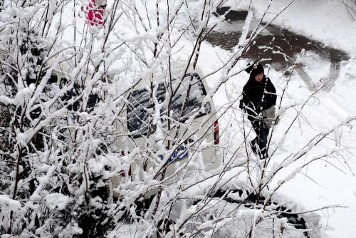 Residents walk in snow in Shenyang, capital of northeast China&apos;s Liaoning Province, on March 15, 2010. A heavy snow hit Shenyang Sunday night, bringing fresh air to the city but causing troubles on the road as well.[Xinhua]