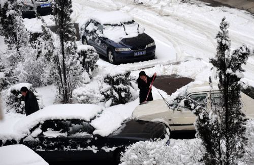 Residents clear snow from their cars before going to work in Shenyang, capital of northeast China's Liaoning Province, on March 15, 2010. A heavy snow hit Shenyang Sunday night, bringing fresh air to the city but causing troubles on the road as well.[Xinhua] 