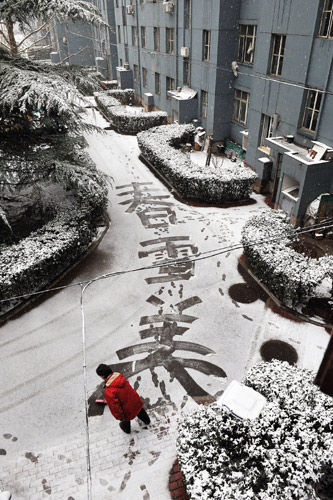 A woman writes Chinese characters meaning 'Spring Snow is Beautiful' in sleet in the Lugu residential area in Beijing, capital of China, March 14, 2010. A sleet hit Beijing Sunday morning. 
