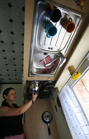 Photo shows a women checks the kitchen items inside a wooden house which is built upside-down in a zoo in Gettorf, northern Germany. [CRI]