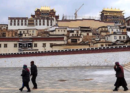 Picture taken on March 14, 2010, shows Tibetan pilgrims praying with prayer wheels outside the Gedan Songzanlin Lamasery in Shangri-La County, southwest China's Yunnan Province. [Xinhua Photo]
