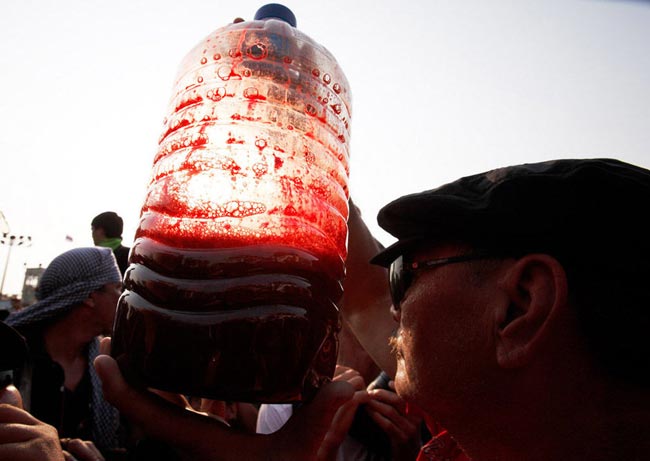  A supporter of deposed Thai Prime Minister Thaksin Shinawatra holds up a canister filled with human blood during a protest outside Government House on March 16, 2010 in Bangkok, Thailand. [163.com]