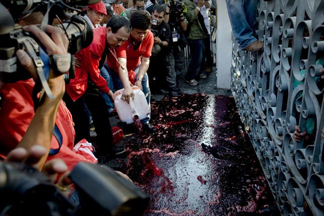 Supporters of deposed Thai Prime Minister Thaksin Shinawatra pour human blood from a cannister beside the gate of Government House on March 16, 2010 in Bangkok, Thailand. [163.com]