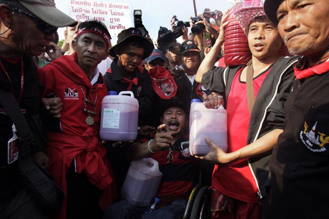 Supporters of deposed Thai Prime Minister Thaksin Shinawatra hold up canisters filled with human blood during a protest outside Government House on March 16, 2010 in Bangkok, Thailand. [163.com]