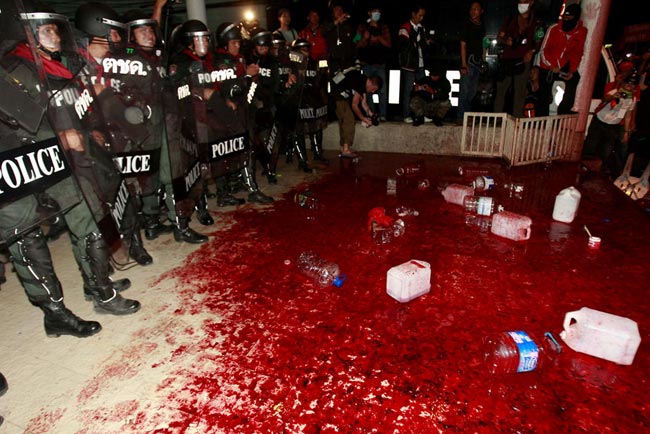 Riot police stand behind a pool of human blood poured by Red Shirt demonstrators in front of the Democrat Party headquarters in Bangkok. [163.com]