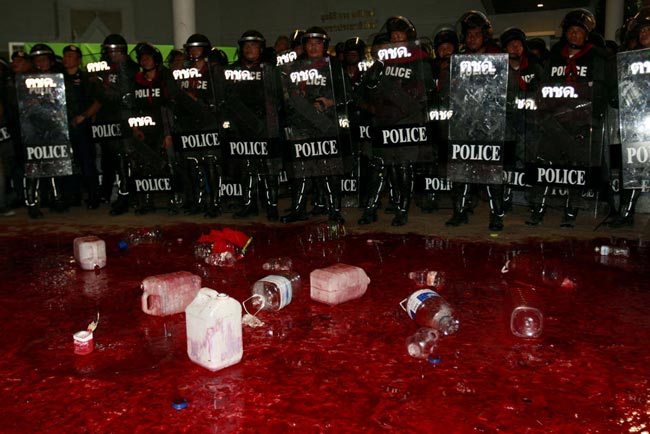 Riot police stand behind a pool of human blood poured by Red Shirt demonstrators in front of the Democrat Party headquarters in Bangkok. [163.com]