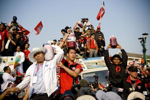 Thai red-shirted demonstrators hold canisters of blood before pouring it on the footpath in front of the ruling Democrat Party's headquarters in Bangkok, capital of Thailand, March 16, 2010. (Xinhua/Lui Siu Wai) 