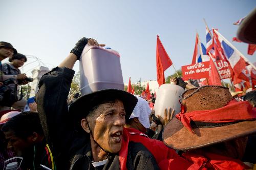 A Thai red-shirted demonstrator holds a canister of blood before pouring it on the footpath in front of the ruling Democrat Party's headquarters in Bangkok, capital of Thailand, March 16, 2010. (Xinhua/Lui Siu Wai)