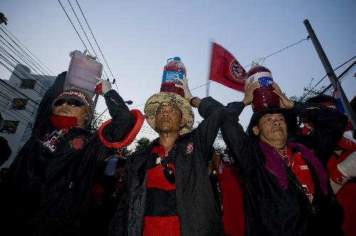 Thai red-shirted demonstrators hold canisters of blood before pouring it on the footpath in front of the ruling Democrat Party's headquarters in Bangkok, capital of Thailand, March 16, 2010. (Xinhua/Lui Siu Wai)
