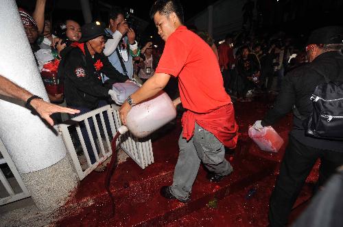 A Thai red-shirted demonstrator pours blood on the footpath in front of the ruling Democrat Party&apos;s headquarters in Bangkok, capital of Thailand, March 16, 2010. The Thai anti-government group here on Tuesday poured the blood donated earlier the day by the &apos;red-shirts&apos;, who are staging a mass rally in an effort to topple the government. [Lui Siu Wai/Xinhua] 