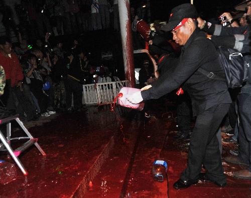 A Thai red-shirted demonstrator pours blood on the footpath in front of the ruling Democrat Party&apos;s headquarters in Bangkok, capital of Thailand, March 16, 2010. The Thai anti-government group here on Tuesday poured the blood donated earlier the day by the &apos;red-shirts&apos;, who are staging a mass rally in an effort to topple the government. [Lui Siu Wai/Xinhua]