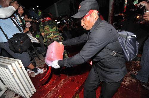 Thai red-shirted demonstrator pours blood on the footpath in front of the ruling Democrat Party&apos;s headquarters in Bangkok, capital of Thailand, March 16, 2010. The Thai anti-government group here on Tuesday poured the blood donated earlier the day by the &apos;red-shirts&apos;, who are staging a mass rally in an effort to topple the government. [Lui Siu Wai/Xinhua]