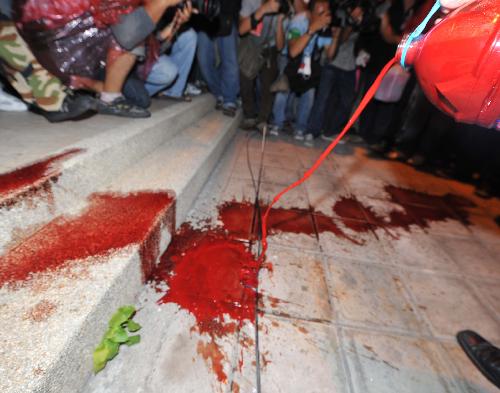 Thai red-shirted demonstrator pours blood on the footpath in front of the ruling Democrat Party&apos;s headquarters in Bangkok, capital of Thailand, March 16, 2010. The Thai anti-government group here on Tuesday poured the blood donated earlier the day by the &apos;red-shirts&apos;, who are staging a mass rally in an effort to topple the government. [Lui Siu Wai/Xinhua]